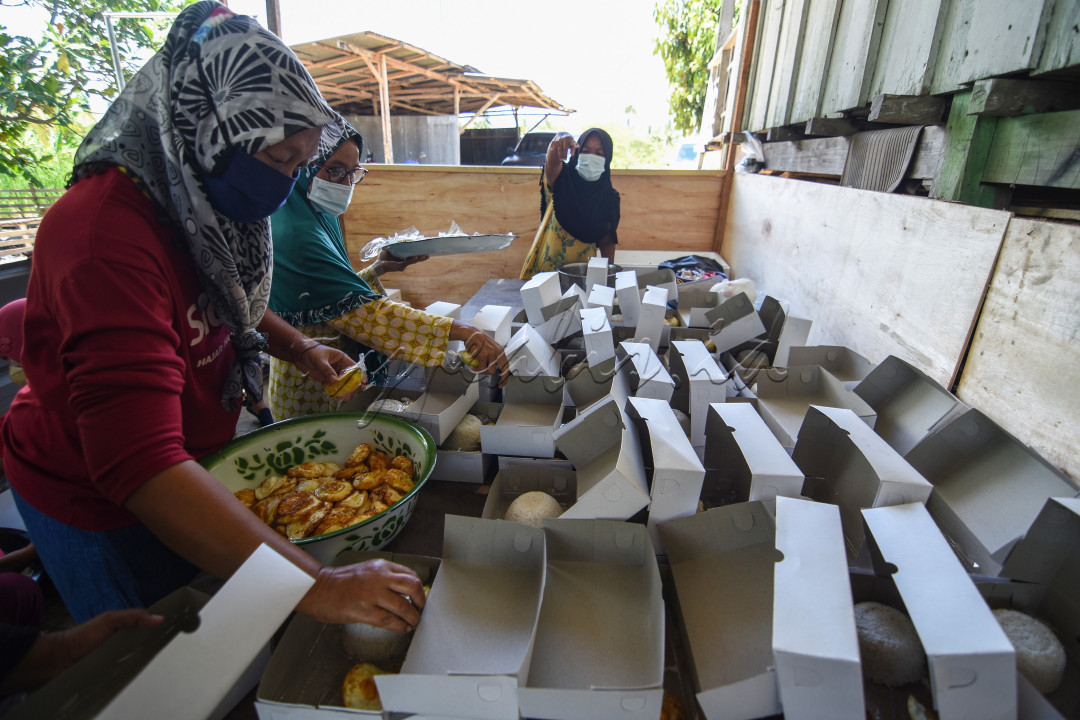 Sejumlah ibu-ibu menyiapkan nasi bungkus untuk warga yang menjalani isolasi mandiri akibat terjangkit Covid-19 di sebuah dapur umum di Dusun 01 Desa Langaleso, Kecamatan Dolo Kabupaten Sigi, Sulawesi Tengah. Dapur umum dengan nama "warga bantu warga" dibuat secara sukarela oleh masyarakat di daerah setempat akibat banyak warga yang menjalani isolasi mandiri. Di dapur umum itu belasan ibu-ibu bergotong royong menyediakan ratusan nasi bungkus untuk warga isoman. 