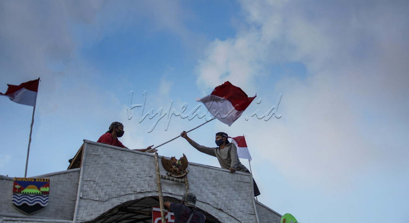 Sekelompok pemuda sedang memasang Bendera Merah Putih di atas Gapura Kemerdekaan , semangat untuk tetap merayakan kemerdekaan Republik Indonesia di tengah Pandemi, jiwa patriotisme ditunjukkan oleh pemuda - pemuda ini merayakan Kemerdekaan dengan tetap mematuhi protokol kesehatan <br />
