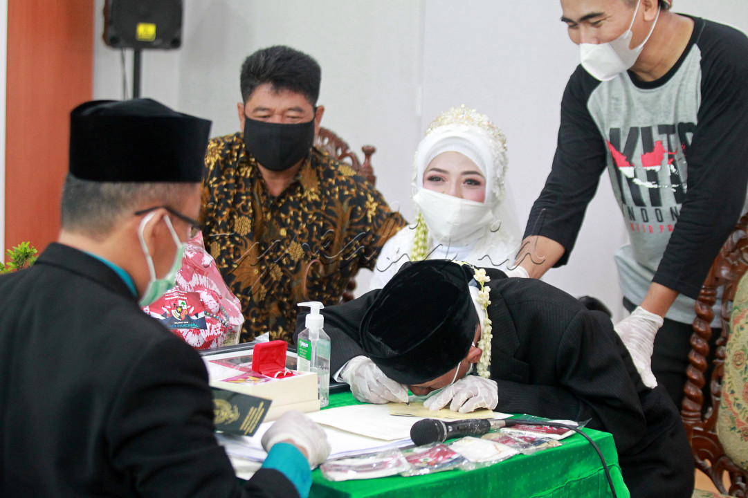 Mujiono, penyandang low vision menandatangani buku nikah disaksikan istrinya Dewi Susilowati, penyandang tunadaksa, saat mengikuti acara Nikah Gratis di KUA Sewon, Bantul, Selasa (8/6/2021). Nikah Bareng Gratis yang digelar oleh Forum Ta'aruf Indonesia tersebut diikuti lima pasang pengantin dan bertujuan untuk meringankan biaya pernikahan dalam masa pandemi Covid-19, seperti cincin, mahar, rias dan busana pengantin. 