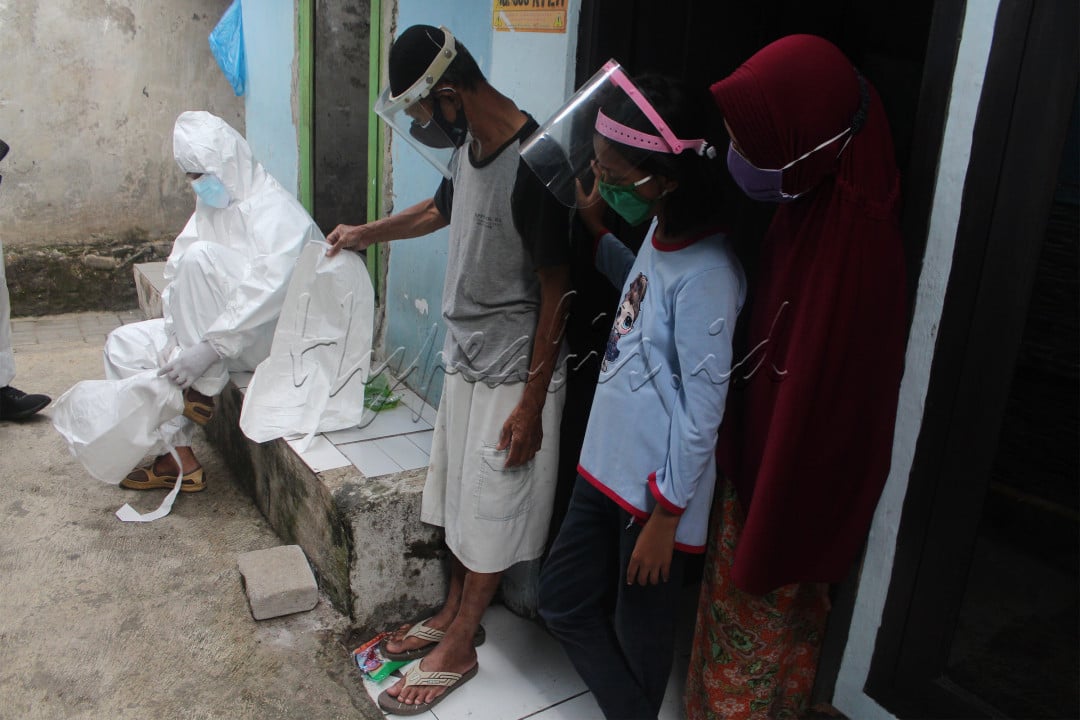 Warga membantu relawan Polmas Bogor memakai Alat Pelindung Diri (APD) untuk bertugas melakukan pemulasaraan jenazah terinfeksi Covid-19 yang meninggal dunia saat Isolasi Mandiri (Isoman) Covid-19 di Desa Batu Tulis, Bogor, Jawa Barat, Minggu (11/7/2021).