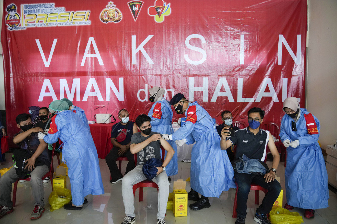 Petugas medis dari Rumah Sakit Brimob Kota Depok menyuntikkan vaksin COVID-19 kepada warga saat vaksinasi massal di Terminal Jatijajar, Depok, Jawa Barat, Jumat (25/6/2021). Pemerintah Kota Depok bersama Kementerian Perhubungan dan Korps Brimob Polri menggelar vaksinasi COVID-19 massal bagi pelaku transportasi dan masyarakat umum dengan target 3.000 orang yang terdiri dari 1.700 pengemudi ojek daring, 300 pelaku transportasi, 150 pengelola Terminal Jatijajar dan 850 masyarakat umum yang berdomisili di Kota Depok. Vaksinasi massal tersebut selain langkah untuk pencegahan penularan COVID-19, juga untuk menyambut HUT Bhayangkara ke-75. Foto: Muhamad Solihin