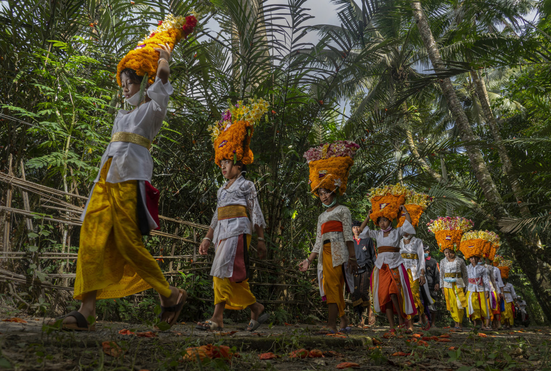 Anak - anak kecil berjalan menuju Pura guna menarikan tarian persembahan, yakni tari Rejang. Di desa Perangsari, Karangasem, Bali, para penari rejang mengenakan hiasan kepala yang menyerupai mahkota. Mahkota yang terbuat dari susunan bunga mitir.
