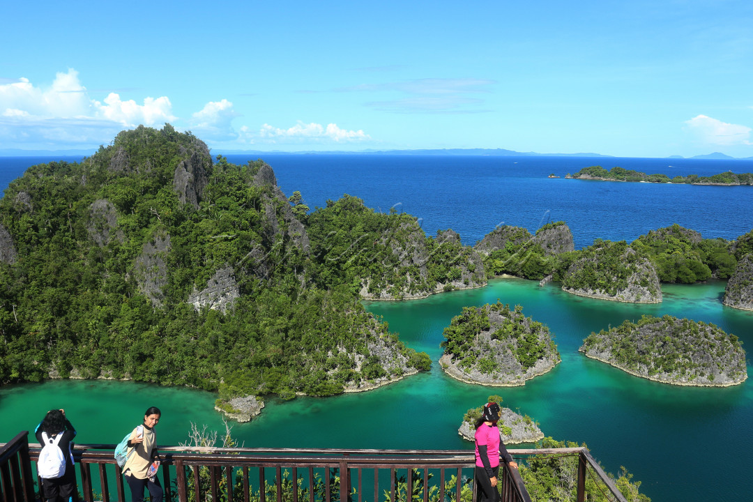 Wisatawan menikmati keindahan pemandangan dari Puncak Piaynemo, Raja Ampat, Papua Barat, Senin (25/10/2021). Pulau dengan julukan Little Wayag (Wayag Kecil) ini menawarkan keindahan dan kecantikan gugusan karst (karang) dari puncak Pianemo dengan ketinggian 59 meter di atas permukaan laut dan 122,4 meter jarak ke puncak. Menapaki 320 anak tangga untuk sampai ke puncak dan menyaksikan langsung pesona keindahan gugusan karang di atas air laut yang berwarna biru.