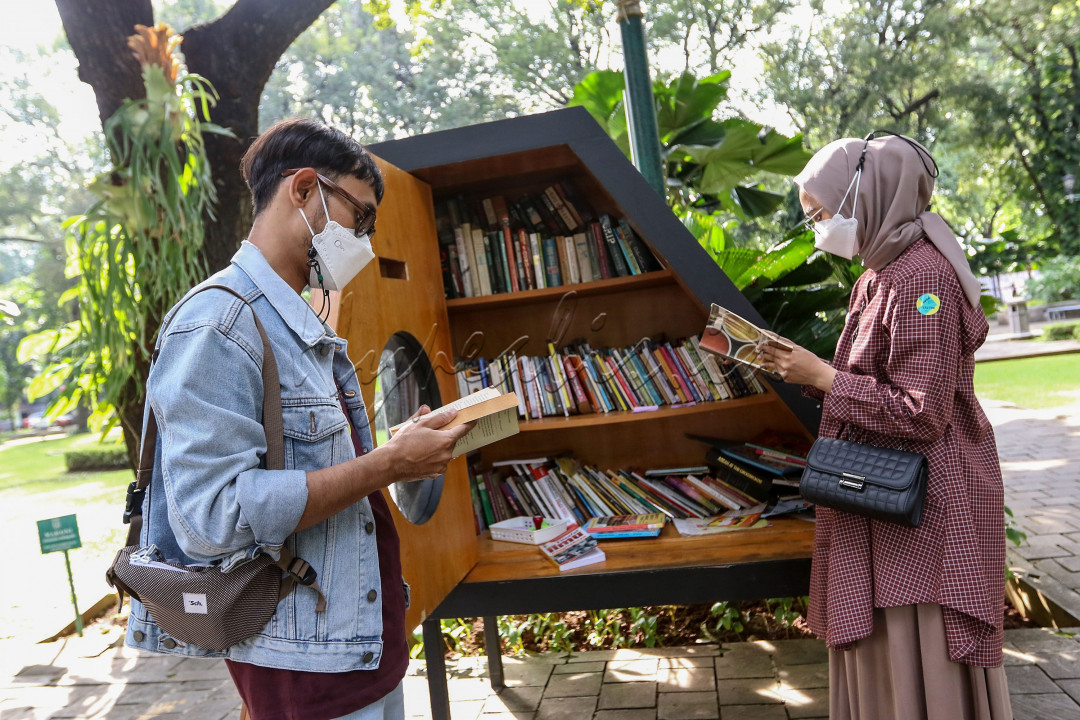 Pengunjung membaca buku di perpustakaan mini Taman Suropati, Jakarta. Membaca buku di ruang terbuka disebut memiliki banyak manfaat, membaca di bawah cahaya terang membuat area otak bisa memproses informasi visual secara lebih efektif. <br />
