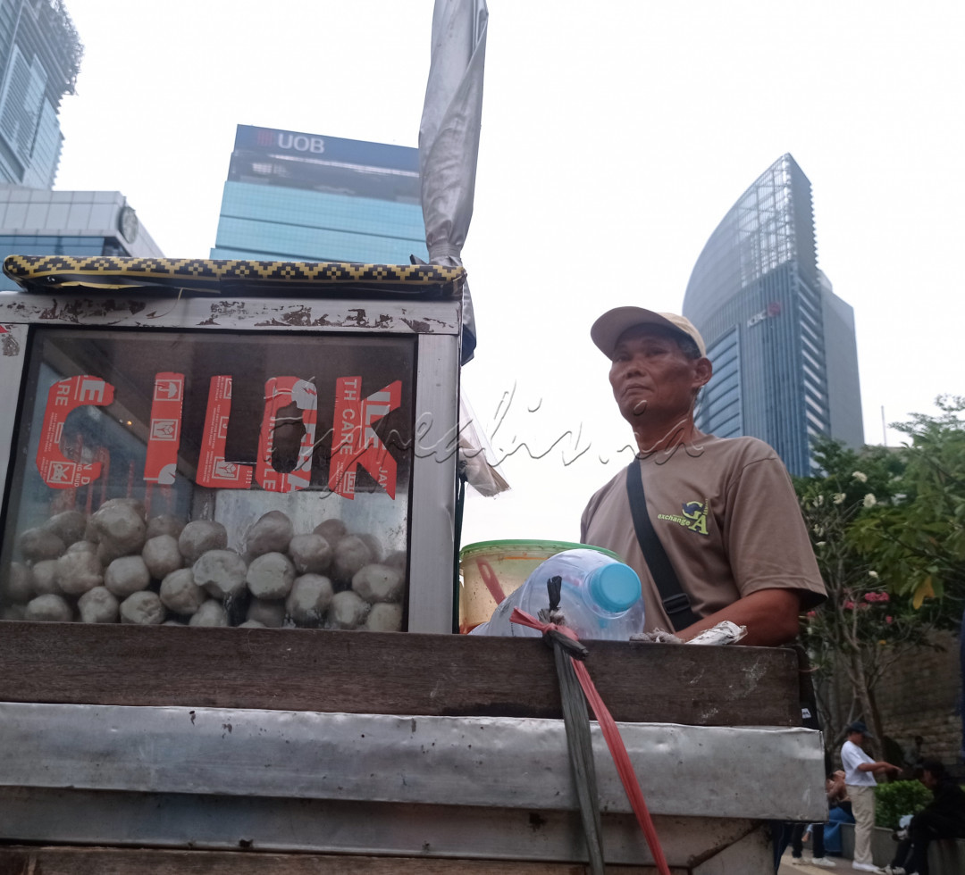 Pedagang cilok sedang menunggu pembeli di jalan Sudirman. 