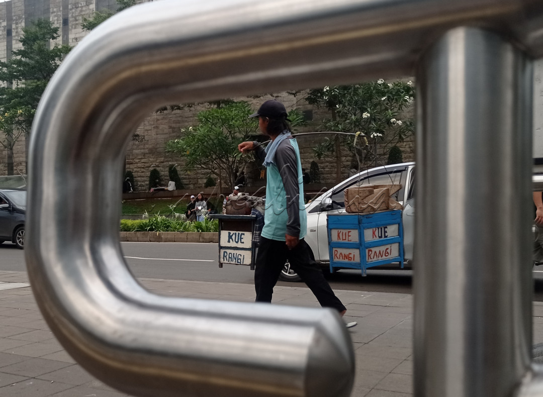 Pedagang kue sedang berkeliling di jalan Sudirman. 
