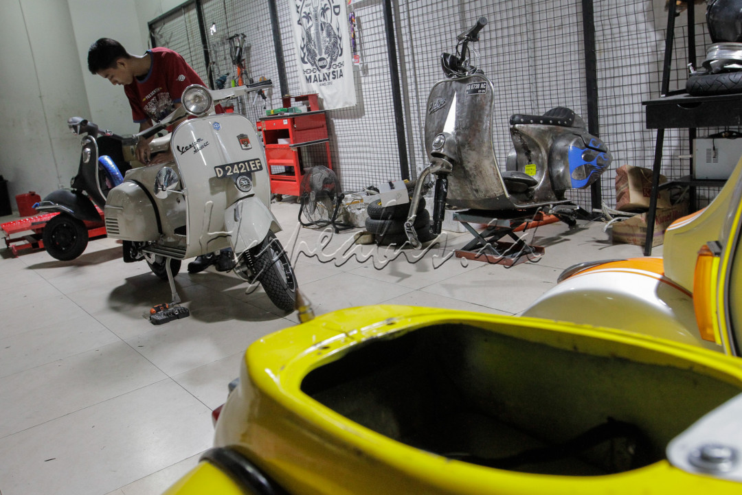 Mekanik memasang baterai pada motor konversi listrik Vespa di Jakarta.