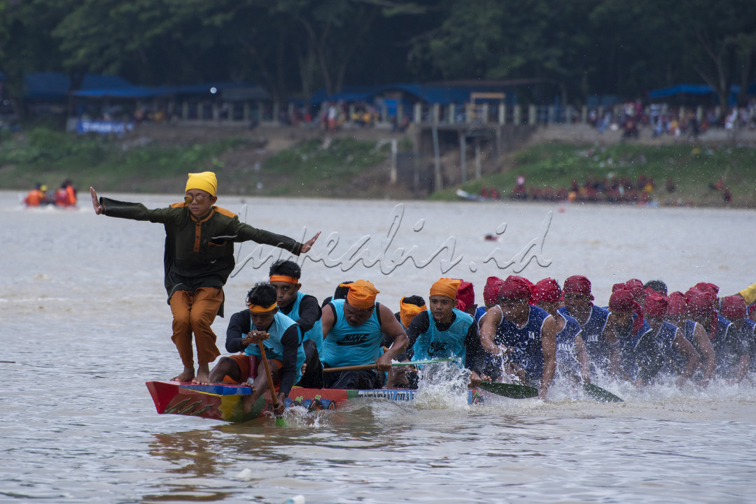 Seorang anak berdiri sambil menari berada di atas sampan untuk memberikan semangat kepada para pedayung dalan Iven lomba Pacu jalur yang di selenggarakan di Kabupaten Kuantan Singingi Provinsi Riau 