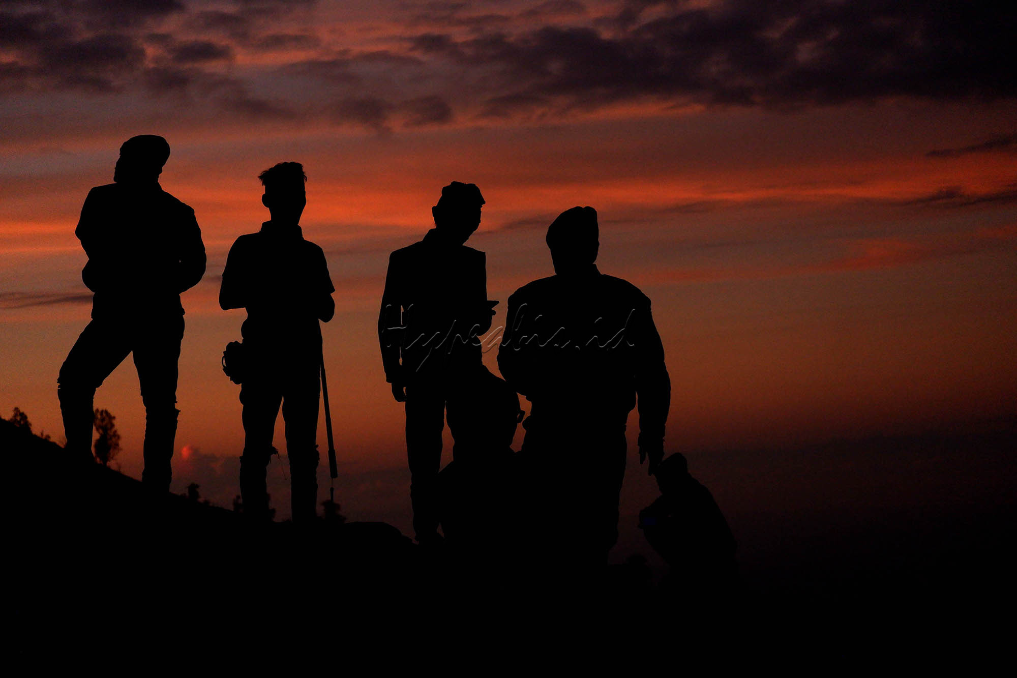 Wisatawan menikmati pagi di kawasan puncak Gunung Ijen, Bondowoso, Jawa Timur. Gunung Ijen berada di kawasan Wisata Kawah Ijen dan Cagar Alam Taman Wisata Ijen dan masih menjadi destinasi wisata populer dan unggulan di Jawa Timur. Kawah Ijen berada di ketinggian 2.368 meter di atas permukaan laut (mdpl). Kawah berdinding kaldera setinggi 300-500m, luasnya sekitar 5.466 hektar. Kawah ini terletak di tengah kaldera terluas di Pulau Jawa. Ukuran kaldera sekitar 20 kilometer. Ukuran kawahnya sekitar 960 meter x 600 meter. Kawah berada di kedalaman lebih dari 300 meter di bawah dinding kaldera. Air kawah itu cukup tenang dan berwarna hijau kebiru-biruan.
